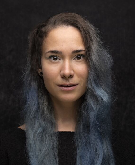 Profile picture of a researcher with long blue hair on dark background